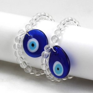 Detail of beaded evil eye bracelets with blue glass charms on a white display stand