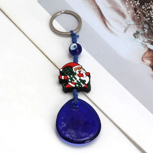 Detail view of Santa Claus charm and blue evil eye pendant on a festive metal keychain