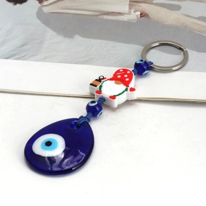 Detail view of Evil Eye keychain with red polka dot gnome and blue glass teardrop charm