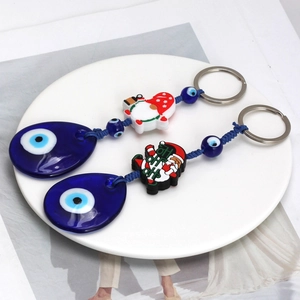 Christmas Evil Eye keychain set with Santa and Gnome charms on a white ceramic plate
