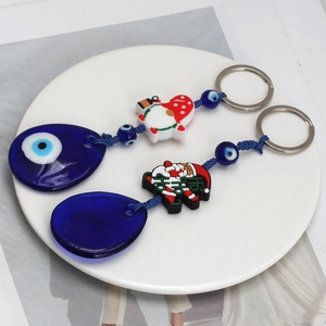 Detail view of Evil Eye Christmas keychains with Santa and Elf charms on a white plate