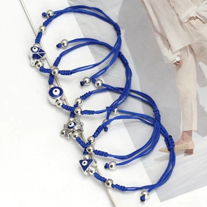 Detailed view of four navy braided bracelets with diverse evil eye charms on a magazine