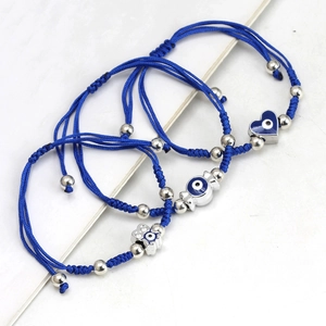 Detailed view of three blue woven evil eye bracelets with heart and floral pendants