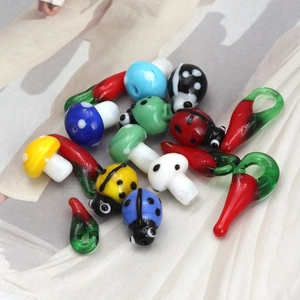 Detail of colorful handmade glass mushroom, ladybug, and chili charms for DIY jewelry making