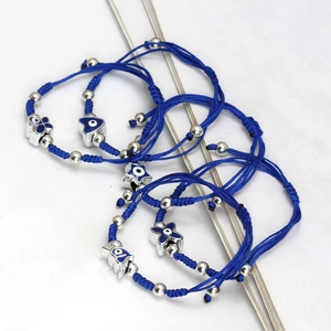 Close-up of blue braided cord bracelets with silver beads and evil eye charms