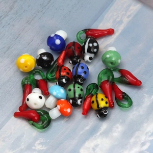 Macro detail of handmade glass mushroom ladybug and chili pendants for DIY jewelry