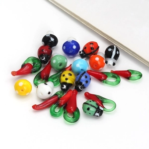 Close-up of handmade lampwork glass beads in ladybug and chili shapes for DIY jewelry making
