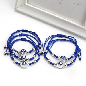 Detail of five-piece blue braided rope bracelets with silver Evil Eye charms and beads