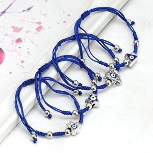 Close-up of four handmade blue braided rope bracelets with various Evil Eye charms