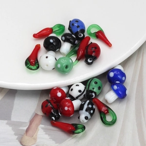 Macro shot of colorful glass mushroom and ladybug charms for DIY jewelry making