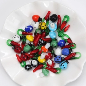 Macro view of colorful glass charms including ladybugs and mushrooms in a white ceramic dish