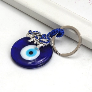 Detailed view of evil eye glass pendant and silver elephant charm with blue rhinestones