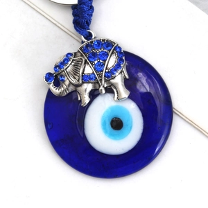 Detail of blue evil eye glass charm with silver elephant and sparkling rhinestones