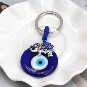 Detail of blue evil eye glass charm and elephant pendant on ceramic plate