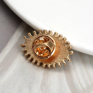 Detailed back view of golden alloy eye brooch showing butterfly clutch and metal texture
