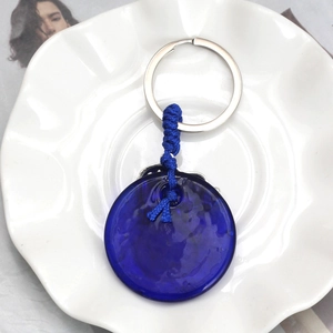 Detailed macro view of deep blue glass round pendant with braided rope on silver keyring