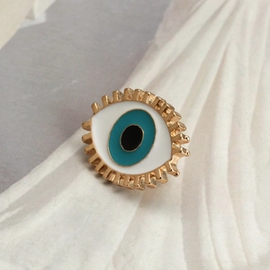 Detailed view of evil eye brooch with golden metal lashes and colorful enamel inlay