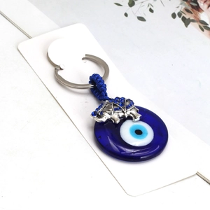 Macro view of blue evil eye glass pendant and silver elephant charm with rhinestones
