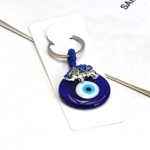 Detail of blue evil eye glass charm with silver elephant and rhinestone accents