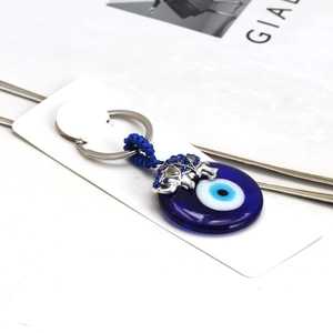 Detail view of silver elephant charm and blue evil eye glass pendant on a keychain