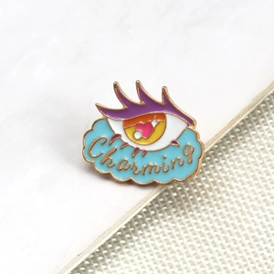 Detailed shot of an eye-shaped brooch with Charming text and blue cloud design