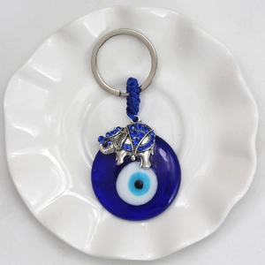 Macro detail of elephant evil eye keychain with blue rhinestones on white ceramic plate