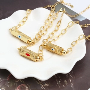 Three gold evil eye necklaces with hexagonal prism pendants on a white ceramic plate