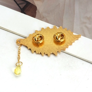 Detail view of gold brooch back with dual butterfly clasps and yellow crystal drop pendant