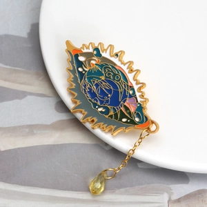 Detailed macro view of an enamel animal brooch with a gold chain and yellow gemstone teardrop
