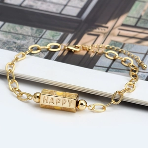 Close-up of gold chain bracelet with HAPPY engraved rectangular beads and heart details