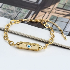 Close-up of rotating evil eye charm on golden chain bracelet with blue crystal
