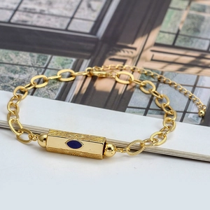Detailed close-up of golden evil eye bracelet with blue center stone and linear textures
