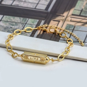 Macro shot of gold bracelet with a rectangular pendant engraved with LIVE and star detail