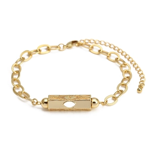 Detail of gold metal bracelet featuring a sunburst rectangle and evil eye cutout design