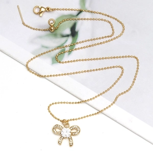 Collier chaîne à billes dorées avec pendentif nœud en zircon et détail Evil Eye