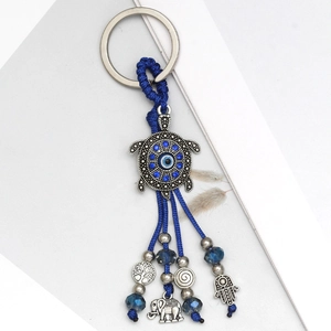 Detail of evil eye turtle keychain with blue tassels and ethnic metal charms pendants