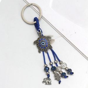 Detail of blue evil eye keychain with turtle, elephant, and Hamsa hand charms