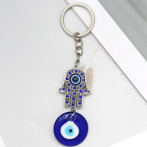 Detailed macro of Hamsa hand keychain with blue rhinestones and glass evil eye charm