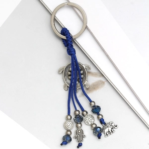 Detail of evil eye keychain with silver turtle, elephant and hamsa hand charms