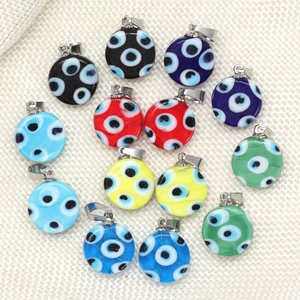 Pendentifs en verre Evil Eye colorés avec crochets argentés sur tissu blanc