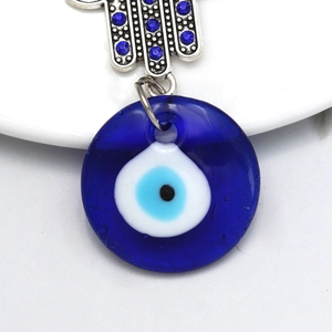 Macro shot of silver Hamsa Hand and blue glass Evil Eye pendant with fine metal texture