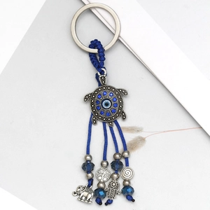 Detail of evil eye turtle keychain with Hamsa hand and elephant charms on blue cords