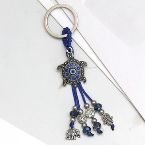 Detail of evil eye keychain with blue turtle, hamsa hand, and elephant metal charms