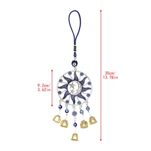 Detailed macro shot of sun and moon metal pendant with evil eye beads and small bells