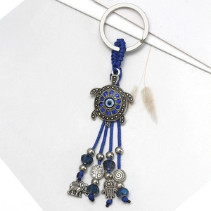 Detail of blue evil eye turtle keychain with elephant and hamsa hand lucky charms