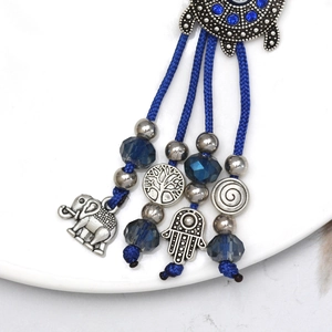 Detailed close-up of blue Hamsa Hand and elephant charms on an ethnic woven keychain