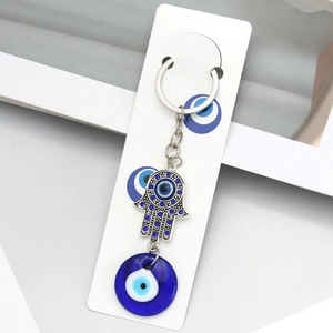 Detail of Hamsa Hand keychain with blue rhinestones and glass Evil Eye bead on display card
