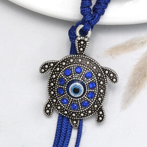 Macro shot of silver turtle pendant featuring the evil eye and blue rhinestones