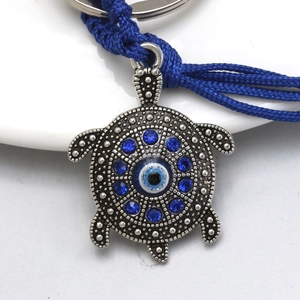 Detail of vintage turtle keychain featuring evil eye bead and dark blue rhinestones