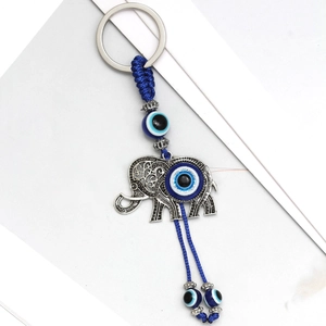Detail of silver elephant keychain with blue evil eye beads and woven cord pendant